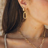 Close up of model wearing the Eden Gold Dangle Earring. This is a gold dangle earring, patterned.