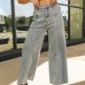 Close up of model wearing the Addilyn Wide Leg Jeans. These are denim jeans, wide leg, frayed hem on bottom, two pockets on back. Option of light wash or black for purchase. 