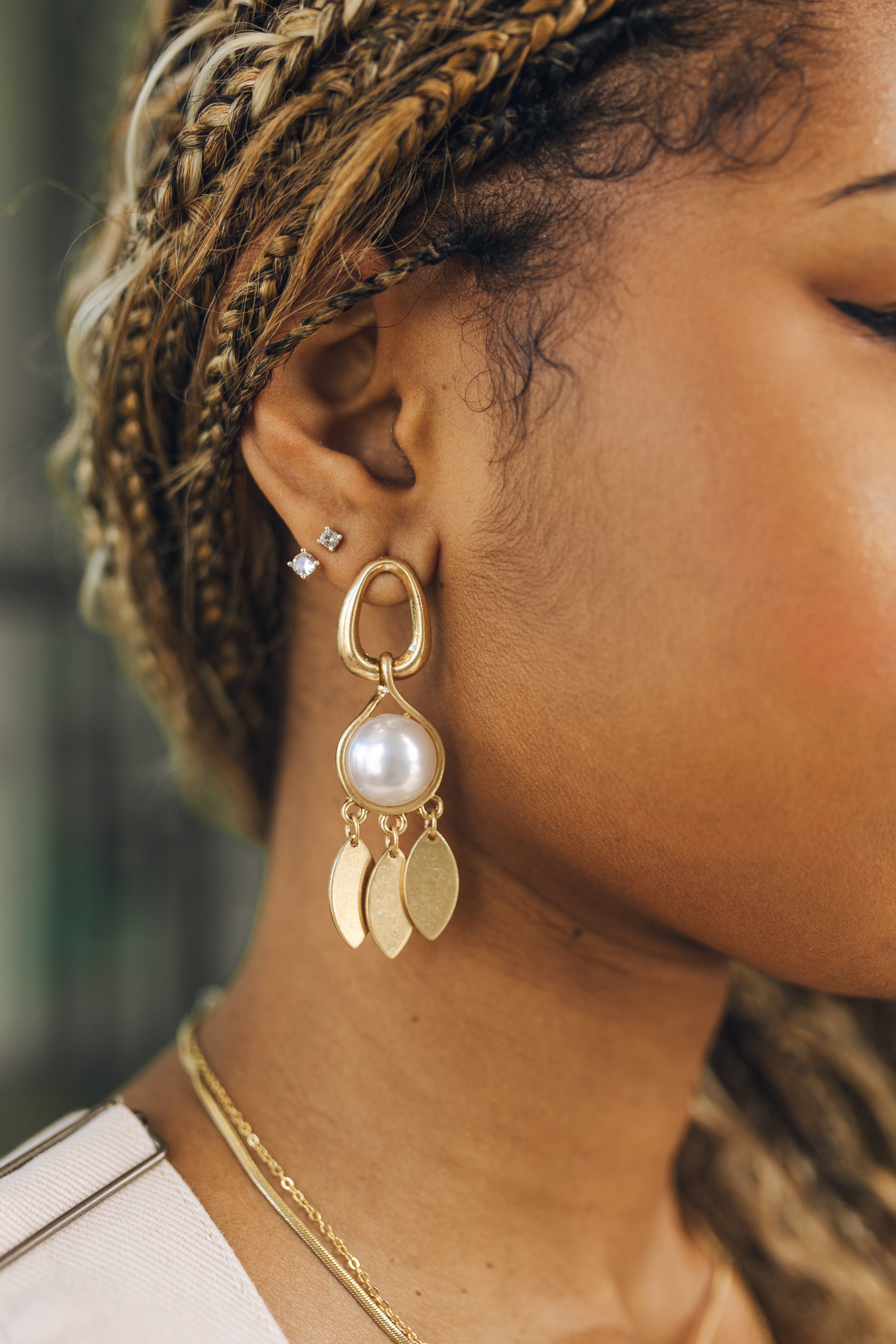 Close up of female model wearing the  Paisley Gold Pearl Earrings. These are gold dangle earrings with white pearl and gold teardrop pendant.