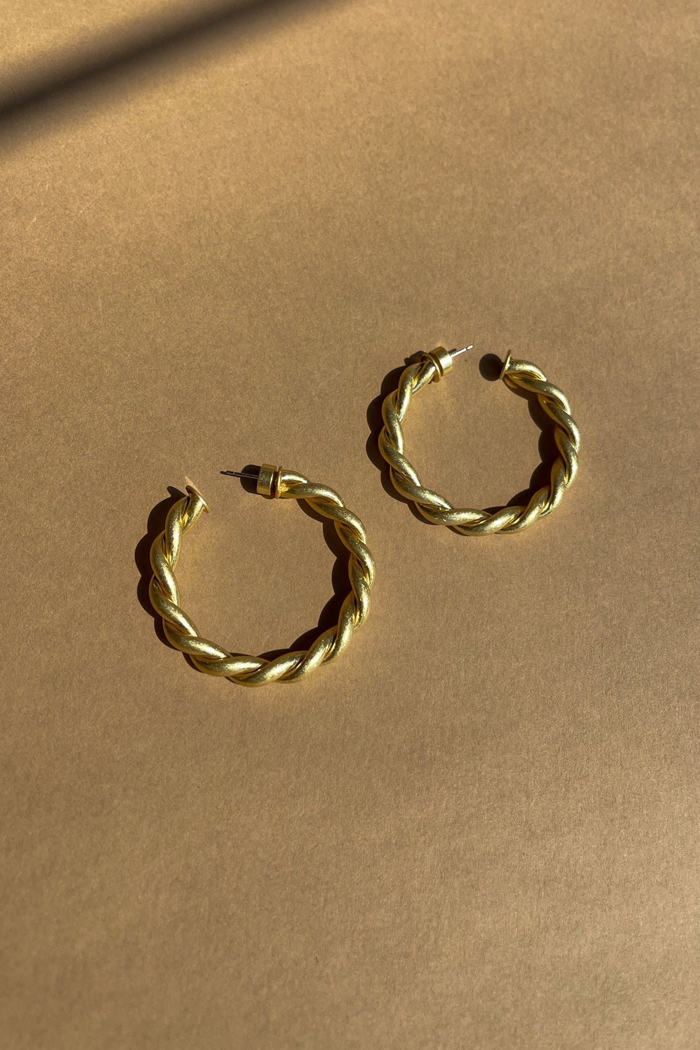 Ramona Twisted Gold Hoop Earrings - close up flat lay view