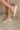 Side view of female model wearing the Kinetic Impact Slide High Wedge Sandal in Honest Beige & Honest White which features Sporty Slip-On Style, Beige and Cream Leather Upper, Two-Tone Scalloped Sole Detail, Molded Rubber Outsole,  2 1/4" Heel Height and 1 1/4" Platform Height