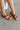 Side view of female model wearing the Kacee Sandal in Dark Brown which features Slingback Slide-On Style, Cushioned Footbed, Burnished Brown, Hand-Finished Upper, Round Toe, 0.5" Platform Height and 0.75" Heel Height
