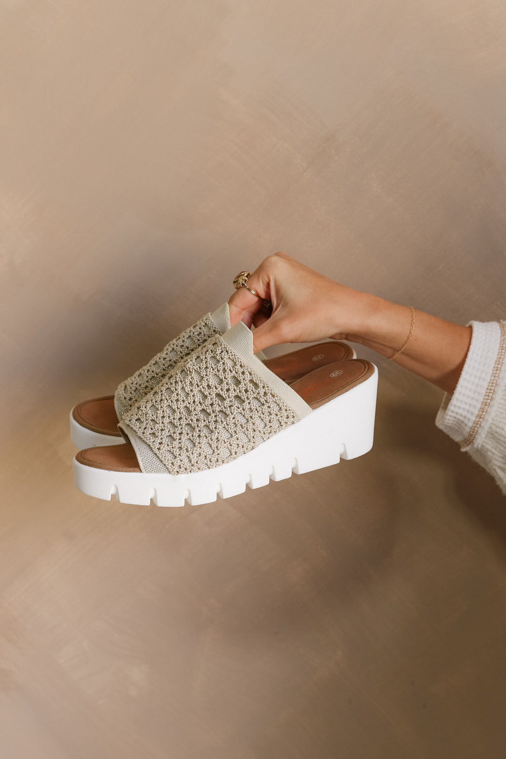 Side view of model holding the Venti Crochet Sandal in Nude Silver which features Crochet Fabric Upper, Slide On Style, Memory Foam Footbed, 2.25 Inch Platform Wedge and Flexible Rubber Outsole