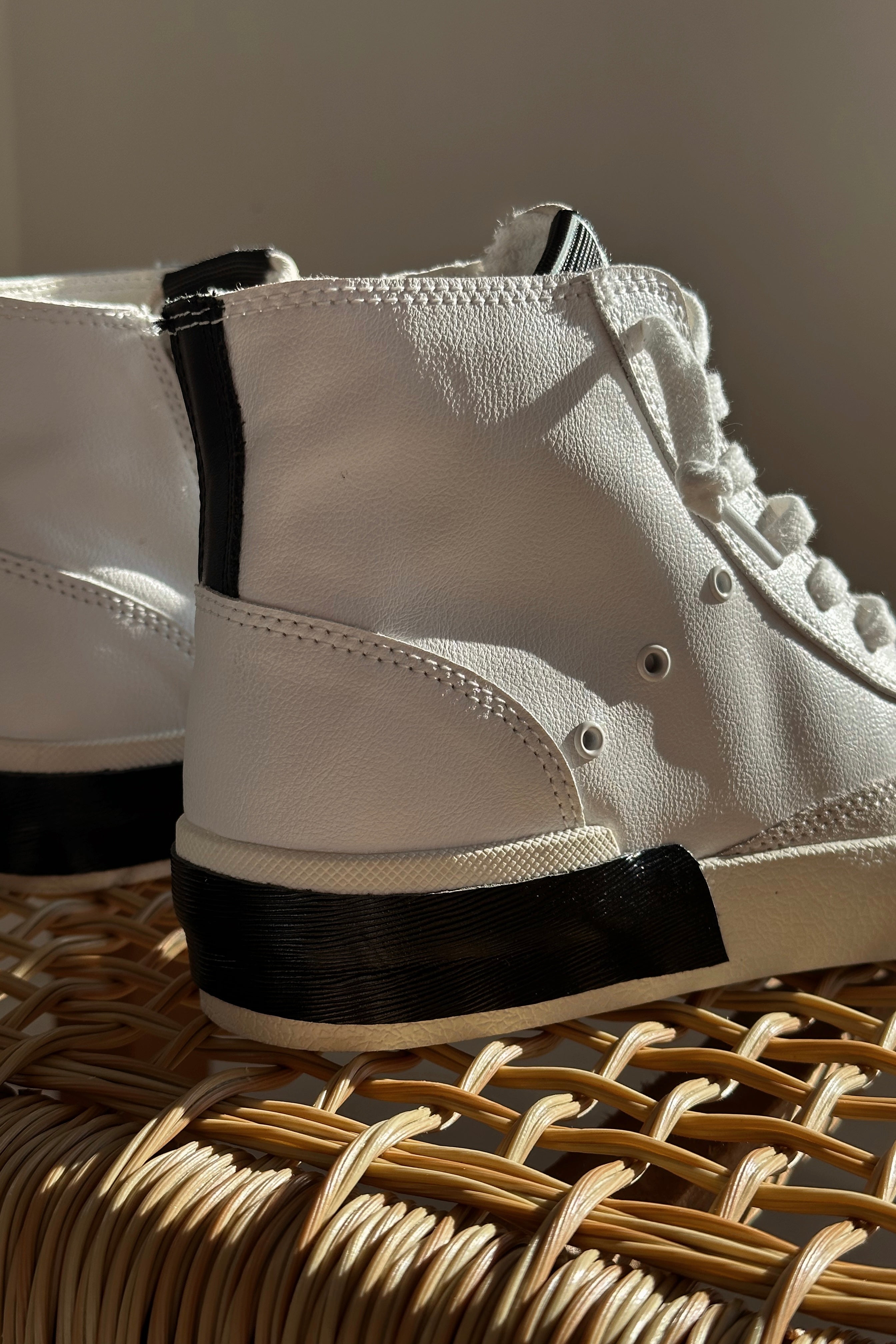 Close up view of the Zohara Sneaker in White Black Leather which features black, brown and white leather upper, off white suede upper, color-block design, high-top style, round toe, lace up details and back zipper closure