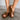 Frontal side view of female model wearing the Moony Bronze Sandal which features Bronze Brown Lightweight Upper, Criss Cross Straps, Slide-On Style, Cushioned Insole and Platform Sole