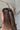 Side view of female model's hair; model is wearing the Melrose Hair Bow Barette in black that has a barrette with a thin black bow..