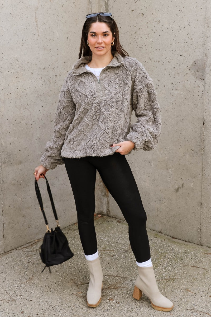 Full body view of model wearing the Layla Grey Quarter Zip-Up Pullover which features soft grey textured fabric with a monochrome geometric pattern, an elastic band, a monochrome quarter zip-up, dropped shoulders, and long balloon sleeves with elastic cuf