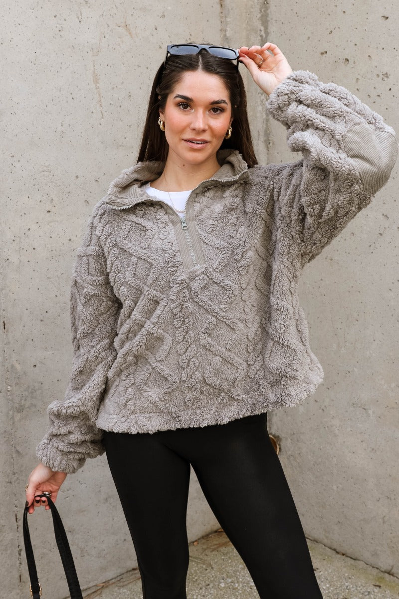 Front view of model wearing the Layla Grey Quarter Zip-Up Pullover which features soft grey textured fabric with a monochrome geometric pattern, an elastic band, a monochrome quarter zip-up, dropped shoulders, and long balloon sleeves with elastic cuffs.
