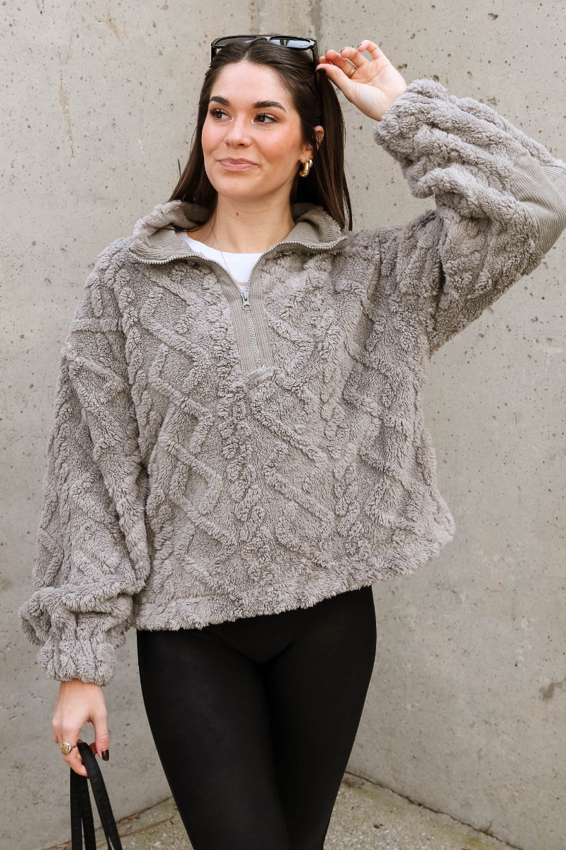 Front view of model wearing the Layla Grey Quarter Zip-Up Pullover which features soft grey textured fabric with a monochrome geometric pattern, an elastic band, a monochrome quarter zip-up, dropped shoulders, and long balloon sleeves with elastic cuffs.