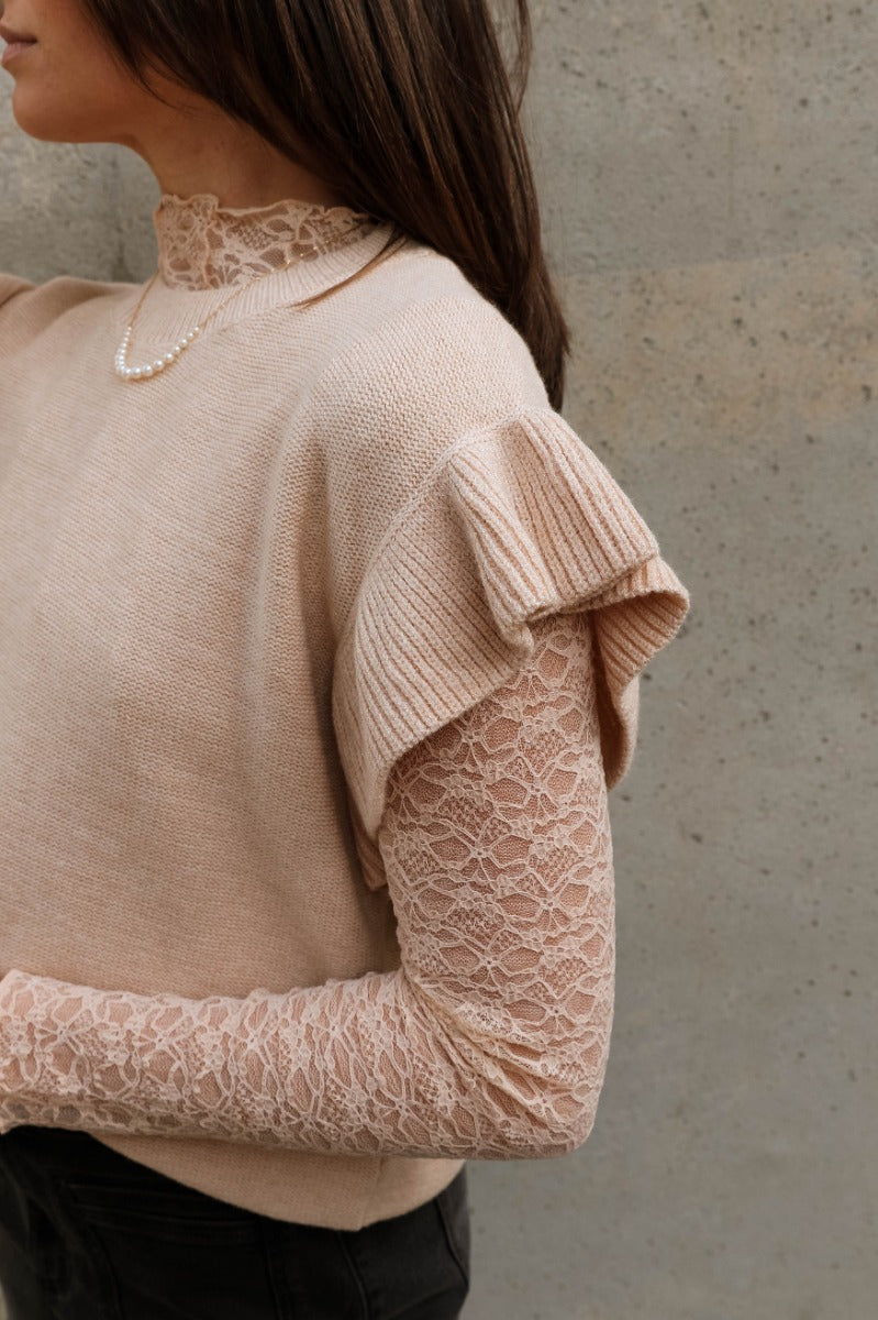 Close up view of model wearing the Sierra Beige Knit Ruffle Sweater which features beige knit fabric, a thick hem, a round neckline, and short sleeves with ruffle trim.
