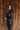 Side view of model wearing the Lyra Black Sequin Long Sleeve Top that has black sequin fabric, black lining, a cropped waist, a round neckline, a back zipper, and long sleeves.