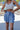 Front view of model wearing the Sunny Skies Skort that has dusty blue lightweight fabric, an elastic waist with drawstring ties, fitted dusty blue shorts, and a skirt overlay with slits on each side