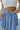 Close front view of model wearing the Sunny Skies Skort that has dusty blue lightweight fabric, an elastic waist with drawstring ties, fitted dusty blue shorts, and a skirt overlay with slits on each side