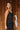 Upper side view of model wearing the Colette Black Floral Satin Midi Dress that has black satin fabric, monochrome florals, a assymetrical ruffle tier design, pleated fabric, a cowl neck, and thin straps.