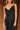 Close upper front view of model wearing the Colette Black Floral Satin Midi Dress that has black satin fabric, monochrome florals, a assymetrical ruffle tier design, pleated fabric, a cowl neck, and thin straps.