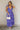 Full body view of model wearing the Harlow Blue & Purple Floral Ruffle Midi Dress which features blue and purple sheer fabric, floral print, light purple metallic, blue lining, three tiered skirt, midi length, plunge neckline, adjustable ruffle straps, op