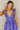 Front view of model wearing the Harlow Blue & Purple Floral Ruffle Midi Dress which features blue and purple sheer fabric, floral print, light purple metallic, blue lining, three tiered skirt, midi length, plunge neckline, adjustable ruffle straps, open b