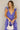 Front view of model wearing the Harlow Blue & Purple Floral Ruffle Midi Dress which features blue and purple sheer fabric, floral print, light purple metallic, blue lining, three tiered skirt, midi length, plunge neckline, adjustable ruffle straps, open b