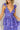 Close up view of model wearing the Harlow Blue & Purple Floral Ruffle Midi Dress which features blue and purple sheer fabric, floral print, light purple metallic, blue lining, three tiered skirt, midi length, plunge neckline, adjustable ruffle straps, ope