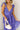 Close up view of model wearing the Harlow Blue & Purple Floral Ruffle Midi Dress which features blue and purple sheer fabric, floral print, light purple metallic, blue lining, three tiered skirt, midi length, plunge neckline, adjustable ruffle straps, ope