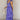 Full body side view of model wearing the Harlow Blue & Purple Floral Ruffle Midi Dress which features blue and purple sheer fabric, floral print, light purple metallic, blue lining, three tiered skirt, midi length, plunge neckline, adjustable ruffle strap