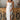 Full body view of model wearing the Falling For You Midi Dress which features white sheer fabric with embroidered white floral print, white skirt lining, tan upper lining, a midi length skirt with a side slit, boning throughout, a sweetheart neckline, adj