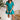 Front view of model wearing the All For You Dress that has teal fabric with a lace floral pattern, mini length, teal lining, a tie around the waist, a surplice neckline, and short puff sleeves with elastic trim