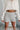 Close-up front view of model wearing the Afterglow Sequin Shorts, which feature a high-rise waist, a silver sequined material, an elastic waist band, and a flowy fit