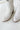 Frontal view of the Untie Ankle Boot that features a white PU material, a traditional western boot silhouette, a shortened shaft, western inspired embroidery, a zipper closure, and a stacked 2" heel.