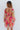 Back view of model wearing the You're A Jewel Floral Dress, which features a multi-colored floral print, a smocked bodice with a sweetheart neckline, long balloon sleeves with elastic wrists, and a tiered skirt