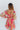 Back view of model wearing the You're A Jewel Floral Dress, which features a multi-colored floral print, a smocked bodice with a sweetheart neckline, long balloon sleeves with elastic wrists, and a tiered skirt