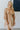 Front view of model wearing the Wonderful Life Dress in Champagne, which features  iridescent fabric, 3/4 balloon sleeves with buttoned cuffs, a v neck and back, and a cutout at the waist