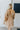 Back view of model wearing the Wonderful Life Dress in Champagne, which features  iridescent fabric, 3/4 balloon sleeves with buttoned cuffs, a v neck and back, and a cutout at the waist