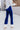 Side view of model wearing the On The Horizon Velvet Pants, which feature cobalt blue velvet, front ankle slits, and a high-rise elastic waist.