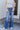 Front view of model wearing the Rooted Denim: Slit Flare Jeans, that feature medium-wash denim with light distressing, flared legs with slits on the outer ankle, and front and back pockets.