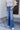 Front view of model wearing the Rooted Denim: Slit Flare Jeans, that feature medium-wash denim with light distressing, flared legs with slits on the outer ankle, and front and back pockets.