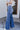 Side view of model wearing the Rooted Denim: Slit Flare Jeans, that feature medium-wash denim with light distressing, flared legs with slits on the outer ankle, and front and back pockets.