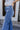 Close-up side view of model wearing the Rooted Denim: Slit Flare Jeans, that feature medium-wash denim with light distressing, flared legs with slits on the outer ankle, and front and back pockets.