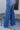 Close-up lower side view of model wearing theRooted Denim: Slit Flare Jeans, that feature medium-wash denim with light distressing, flared legs with slits on the outer ankle, and front and back pockets.