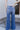 Back view of model wearing the Rooted Denim: Slit Flare Jeans, that feature medium-wash denim with light distressing, flared legs with slits on the outer ankle, and front and back pockets.