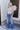 Full body front view of model wearing the Rooted Denim: Slit Flare Jeans, that feature medium-wash denim with light distressing, flared legs with slits on the outer ankle, and front and back pockets.