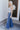 Full body side view of model wearing the Rooted Denim: Slit Flare Jeans, that feature medium-wash denim with light distressing, flared legs with slits on the outer ankle, and front and back pockets.