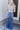 Full body back view of model wearing the Rooted Denim: Slit Flare Jeans, that feature medium-wash denim with light distressing, flared legs with slits on the outer ankle, and front and back pockets.