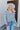 Front view of model wearing the Around The Block Sweater, which features grey knit fabric with pink colorblock details on the wrist and neckline, a v neck and back, and long sleeves.