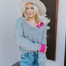 Front view of model wearing the Around The Block Sweater, which features grey knit fabric with pink colorblock details on the wrist and neckline, a v neck and back, and long sleeves.