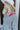 Close-up side view of model wearing the Around The Block Sweater, which features grey knit fabric with pink colorblock details on the wrist and neckline, a v neck and back, and long sleeves.