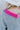 Close-up back view of model wearing the Around The Block Sweater, which features grey knit fabric with pink colorblock details on the wrist and neckline, a v neck and back, and long sleeves.