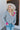 Front view of model wearing the Around The Block Sweater, which features grey knit fabric with pink colorblock details on the wrist and neckline, a v neck and back, and long sleeves.