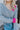 Close-up front view of model wearing the Around The Block Sweater, which features grey knit fabric with pink colorblock details on the wrist and neckline, a v neck and back, and long sleeves.