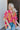 Front view of model wearing the Feeling Fine Top, which features a brown, pink, and orange swirl print, a high neckline, half-length sleeves, and a flowy fit. Shirt styled with front tuck
